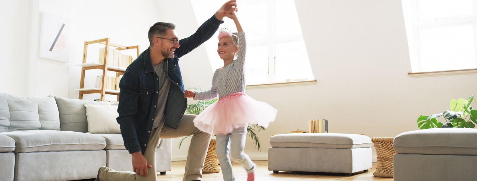 A father twirls his daughter, who is dressed up as a ballerina.